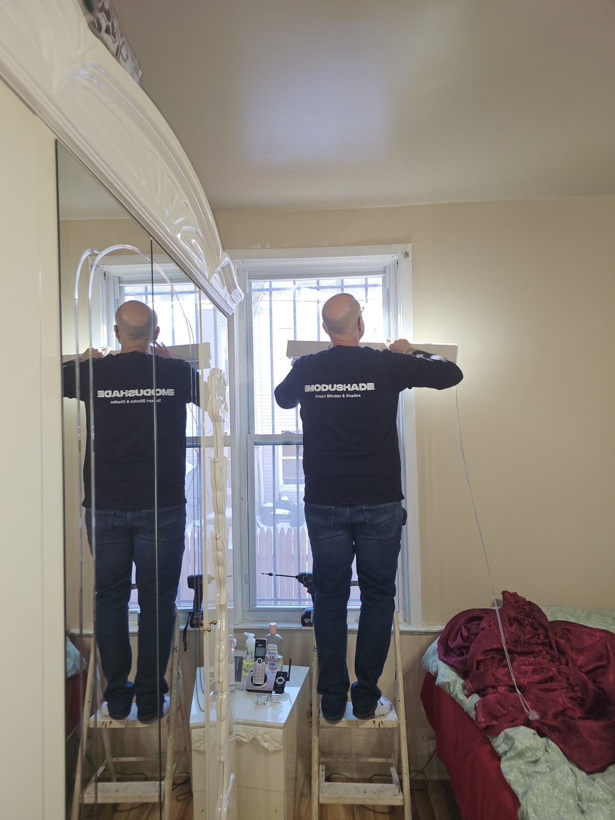 ModuShade installers fitting a shade at a tall arched window from a ladder