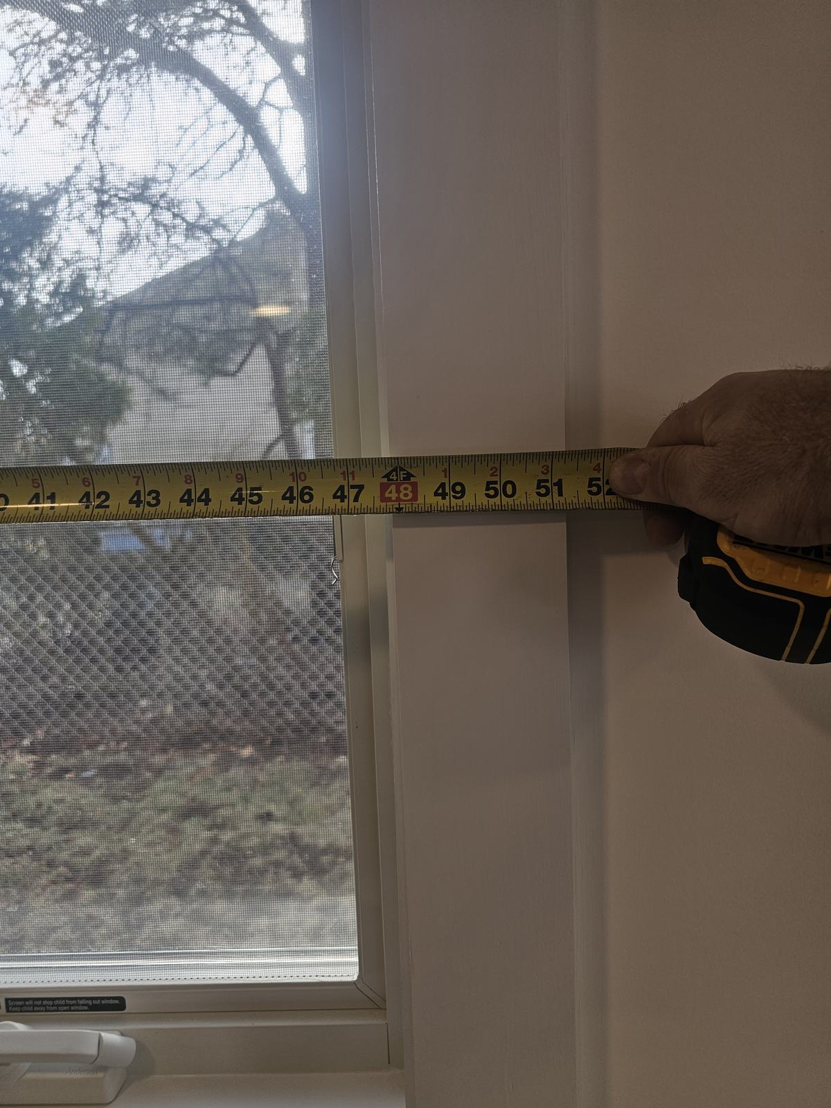 Installer measuring a window opening with a tape measure before ordering motorized shades