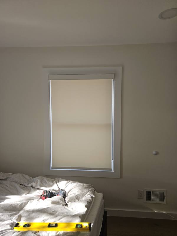 Newly installed roller shade lowered over a bedroom window on install day