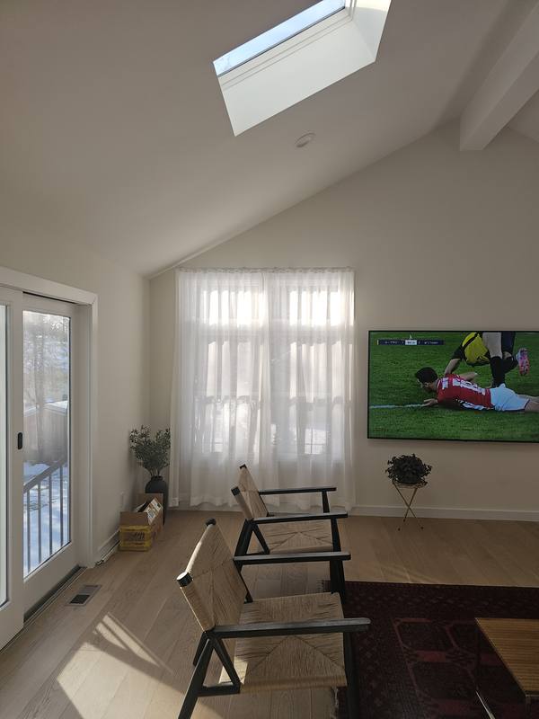 Sheer curtains drawn across a living room door window in a room with a vaulted ceiling and skylight