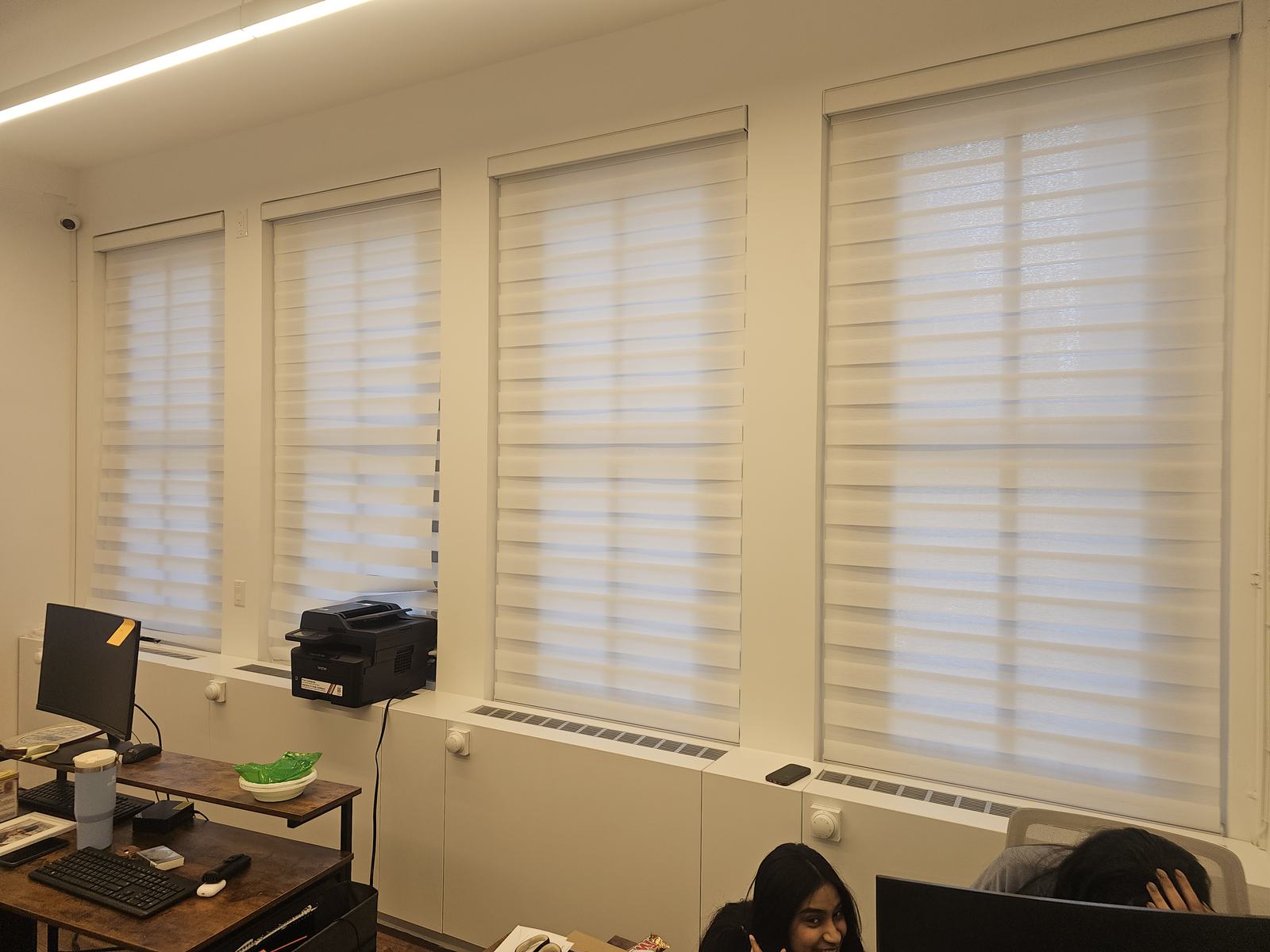 Zebra shades fitted across a row of office windows above desks in a commercial workspace